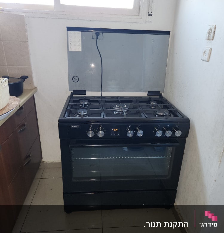 תנור גז שחור עם כפתורים וכיריים עליונים